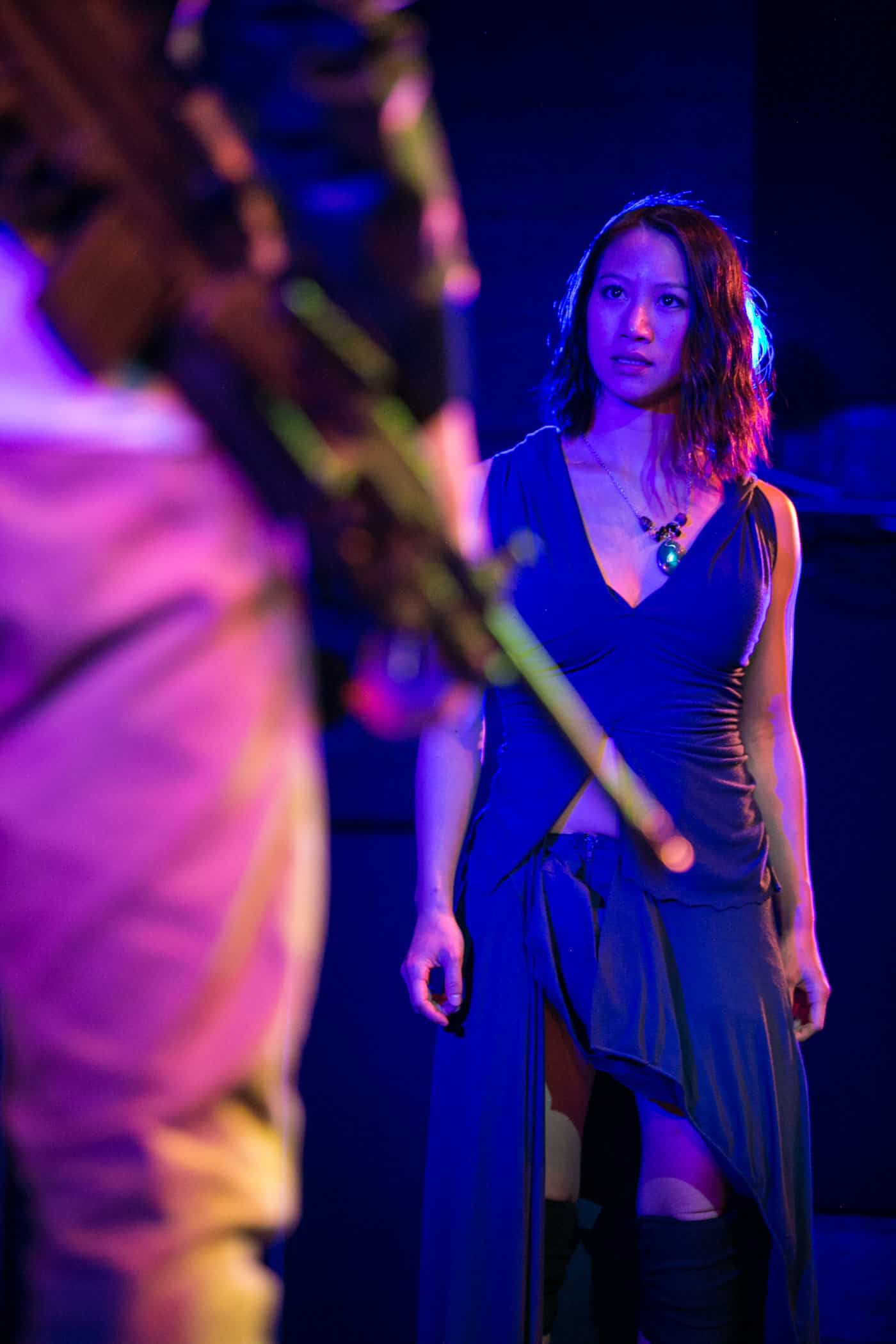 Production image from "Bagyo" at TheatreFIRST, a woman stares down a gunman