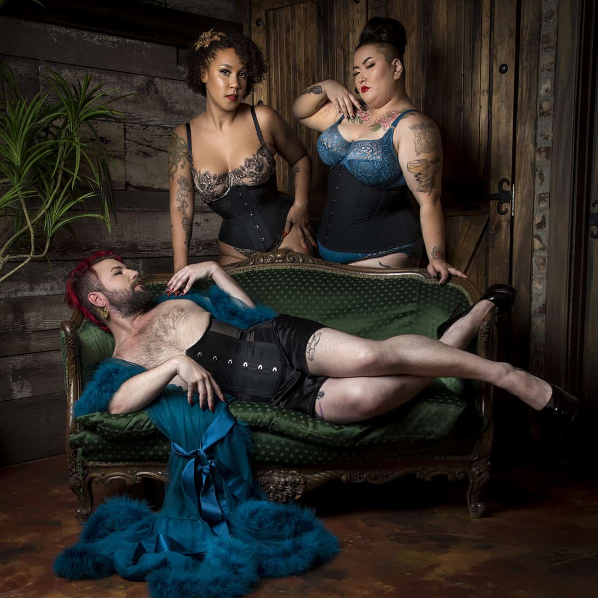 promotional image for Dark Garden, a bespoke corset company: three people wearing Dark Garden designs in a classic speakeasy environment