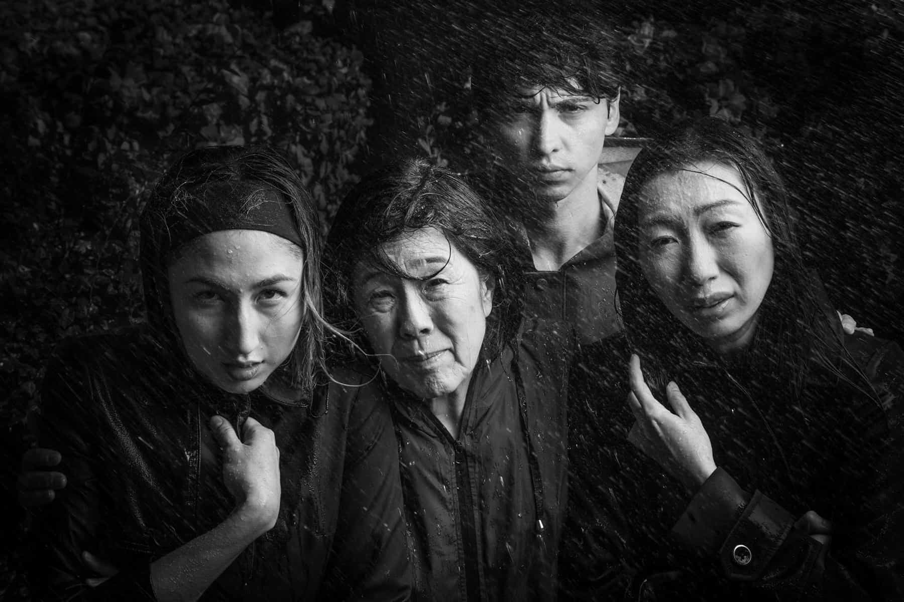 promotional image for "The Great Wave" at Berkeley Rep: four people huddled in a rainstorm getting drenched, lit dramatically