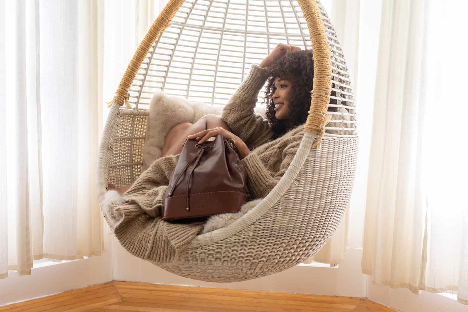 woman in hanging chair with leather purse