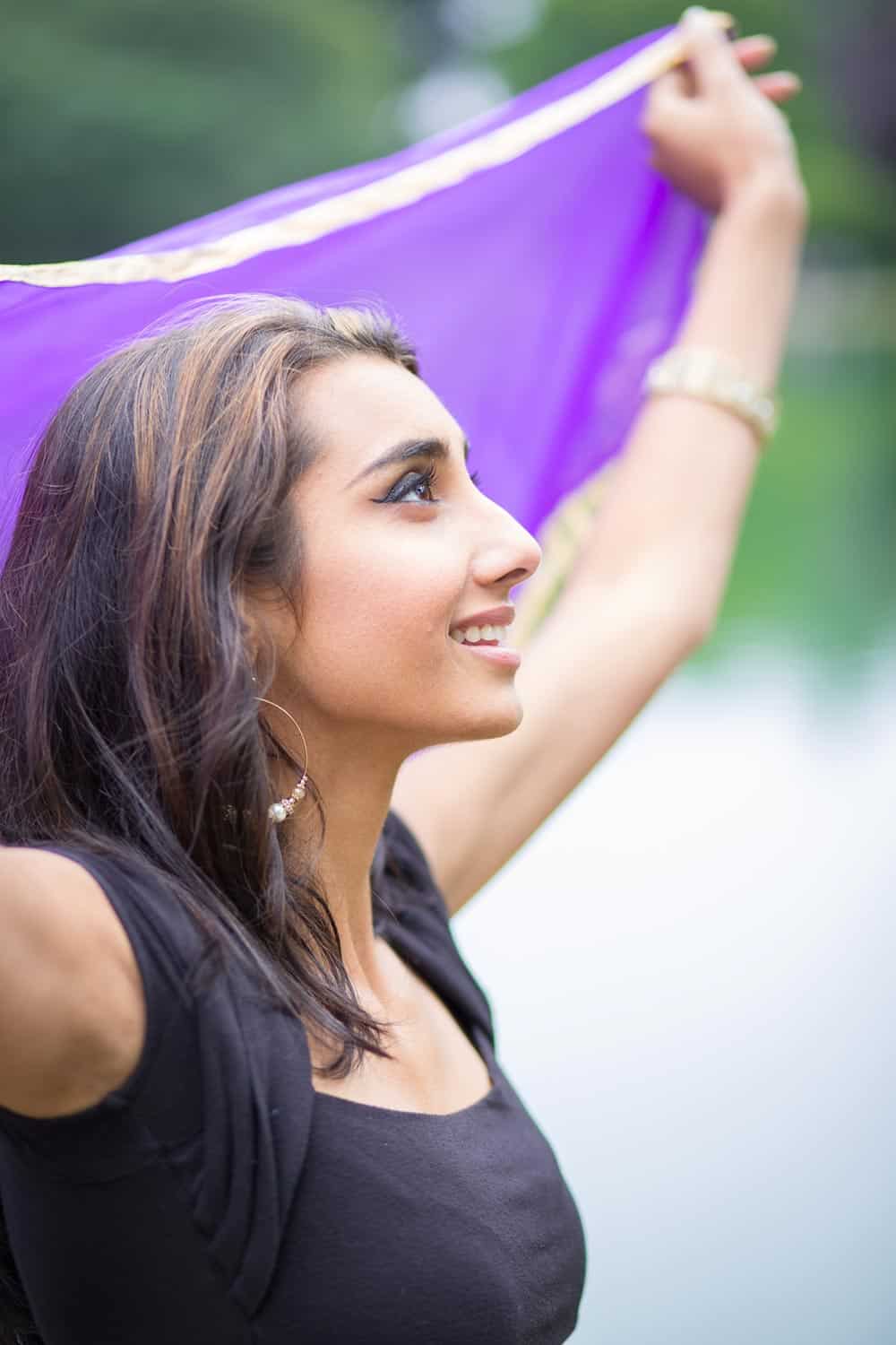 South Asian woman holding up colorful scarf with her head lifted to the sky and a happy expression